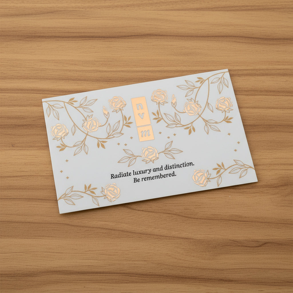 White business card with gold floral designs and text on a timber background